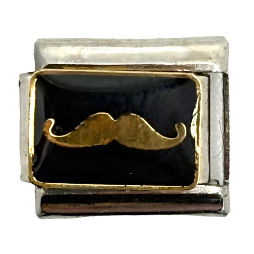 Silver charm with a black background and gold mustache design on a white background